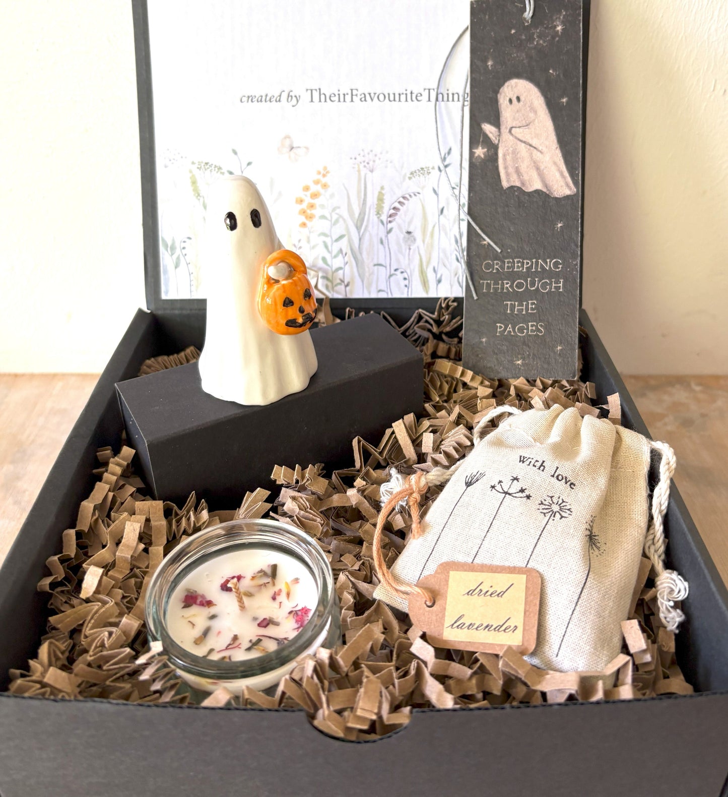 Gift box with Halloween-themed items including a ghost figurine, candle, and lavender bag.